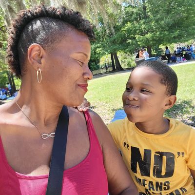 A woman and a boy sharing a joyful moment outdoors on a sunny day.