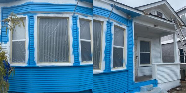 House mid-painting with blue and white colors, windows covered in plastic.
