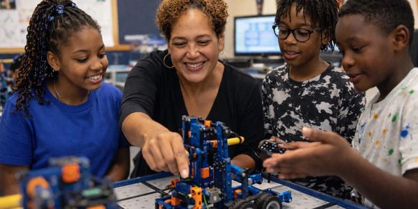 Teacher and students engaged in a robotics activity in a classroom.