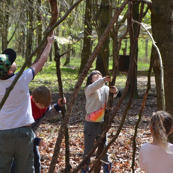 Children making a den with large sticks at Fat Squirrel Outdoor