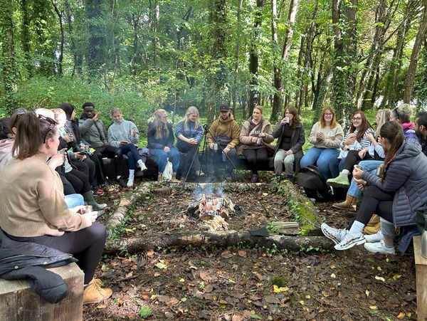 Large corporate group enjoying time together around a campfire at Fat Squirrel Outdoor