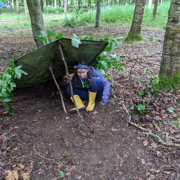 Young girl in yellow wellies under a tarp shelter at a kids campfire party