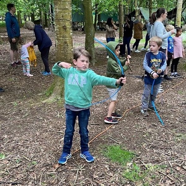 Young lad pulling back a bow to shoot a soft arrow at a Kids campfire party at Fat Squirrel Outdoor