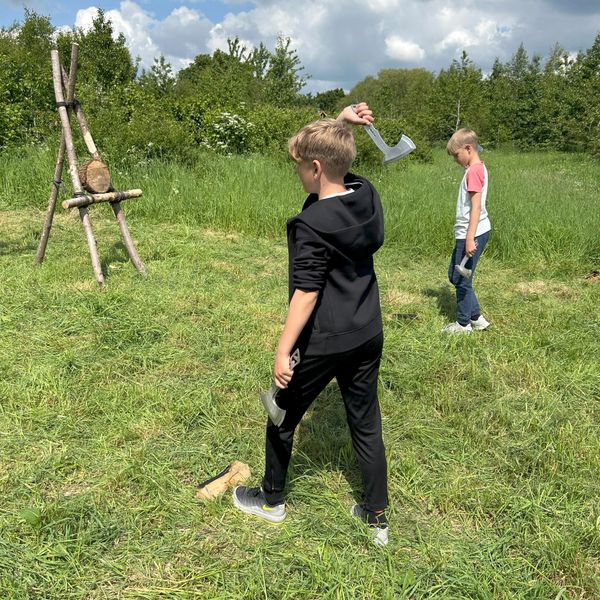 Two boys throwing axes at a Fat Squirrel Outdoor campfire party