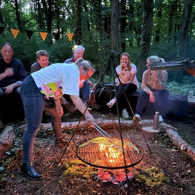 Group of adult friends celebrating a 50th birthday by cooking on a campfire at Fat Squirrel Outdoor