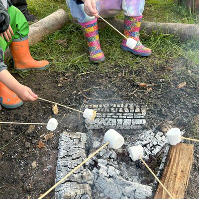 Kids in brightly coloured wellies toasting marshmallow at a kids campfire party at Fat Squirrel