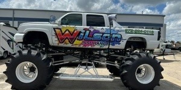 Big truck with large tires and Wilson Insurance branding.