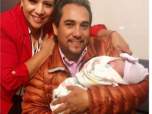 Happy couple with their newborn baby wrapped in a blanket.