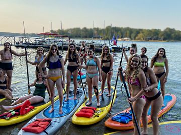 group of young women standing on colorful paddle boards