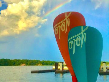 the end of paddle board paddles held up agains the background of a sky with a rainbow in the sky