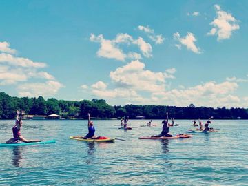 a group of people doing yoga on a lake while on paddle boards
