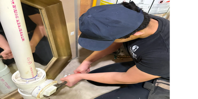 Person fixing plumbing pipe with wrench.