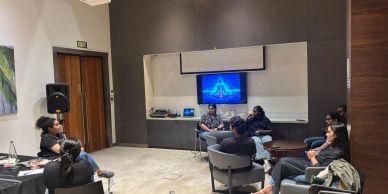 People attending a meeting with a presentation on screen.