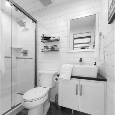 Small modern bathroom with white walls, glass shower, and floating vanity.