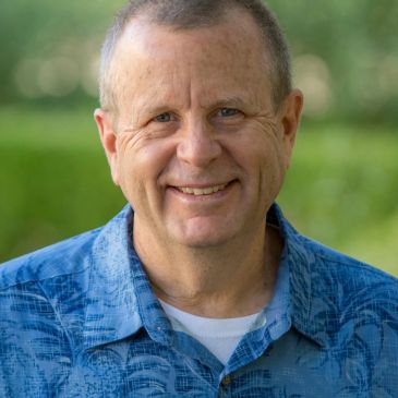Smiling middle-aged man outdoors in blue shirt.