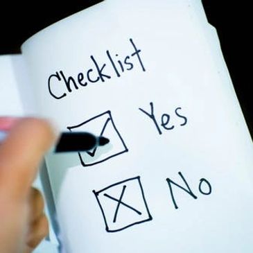 Hand marking a checklist with yes and no options.