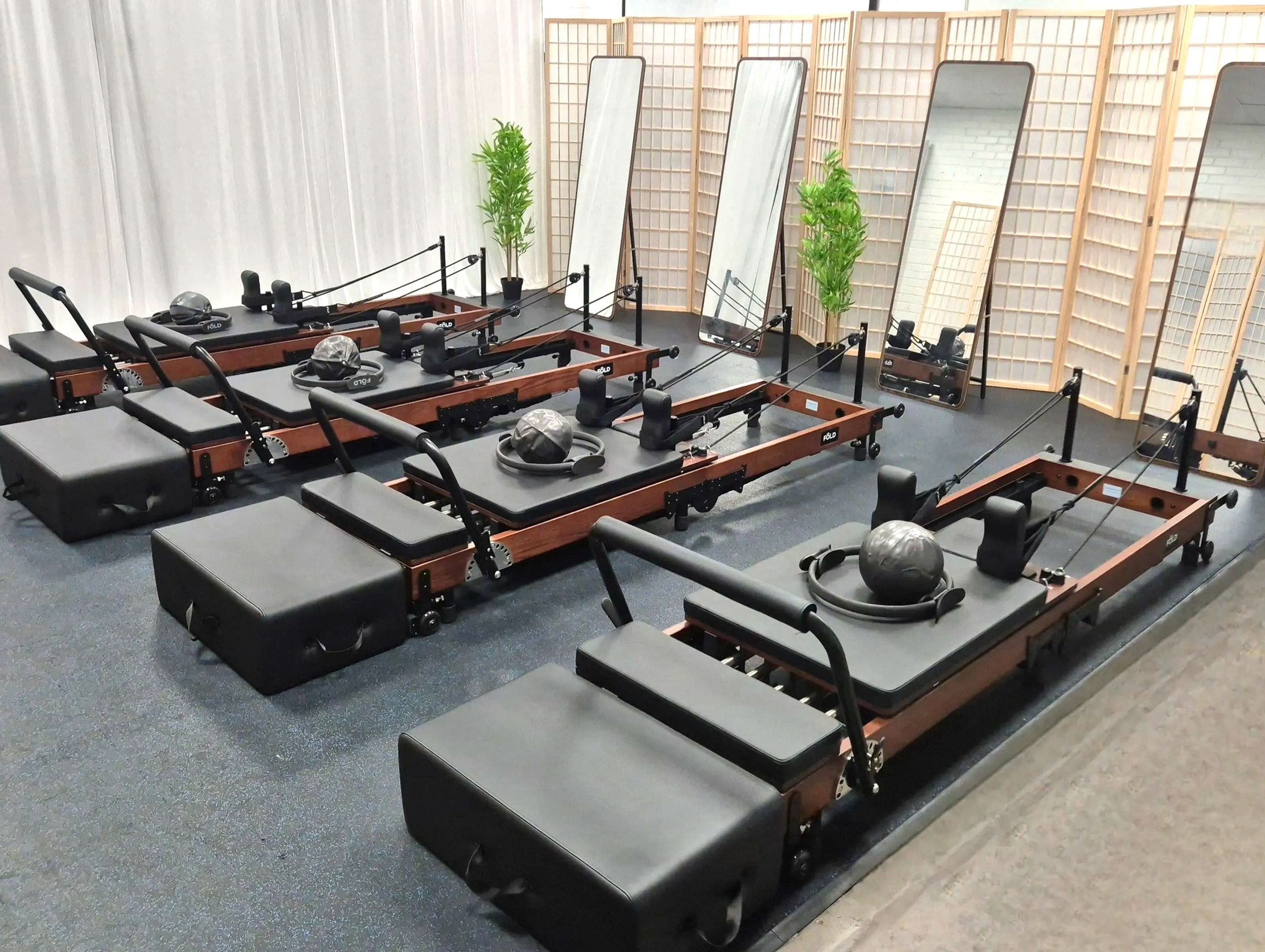 Four reformer beds in a small boutique studio with a Pilates ring and ball resting on the carriage.