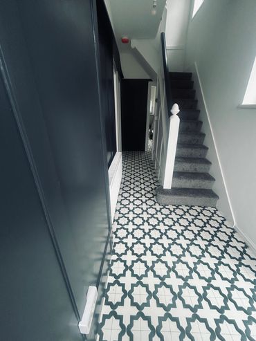 Modern hallway with patterned tile flooring and carpeted stairs.