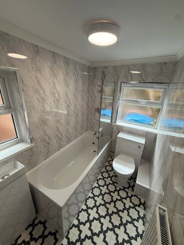Modern bathroom with patterned tile floor and marble walls.