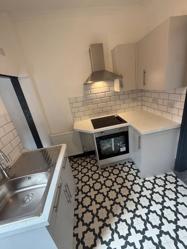 Modern kitchen with patterned black and white floor tiles and white cabinets.