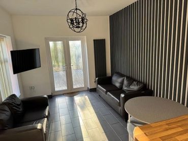 Modern living room with leather sofas and striped accent wall.