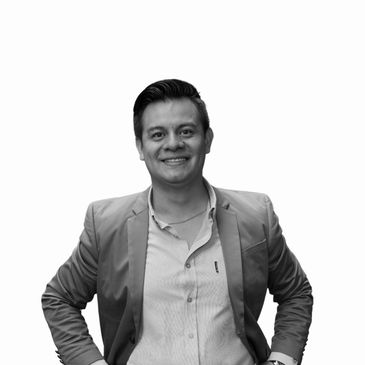 Smiling man in a blazer and shirt, hands on hips, against a white background.