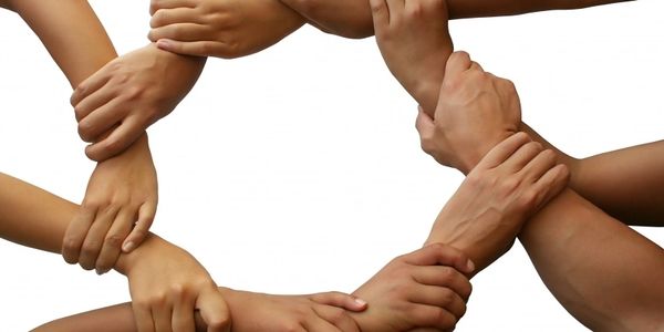 Manos entrelazadas formando un círculo, simbolizando unidad y trabajo en equipo.