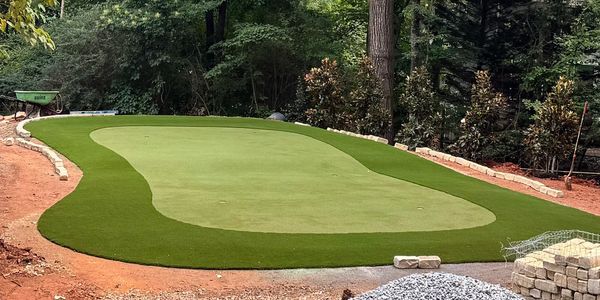 A newly constructed putting green in a wooded area.
