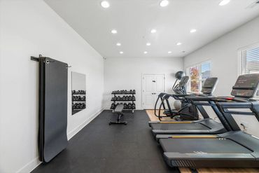 Bright, modern gym with treadmills, dumbbells, mats, and a bench.