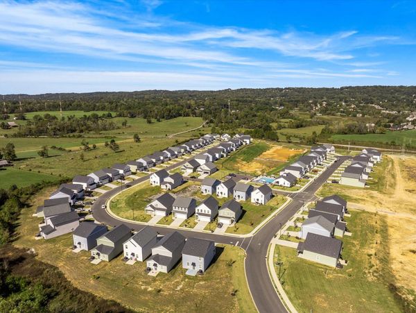 Aerial view of a suburban neighborhood with rows of houses and green fields.