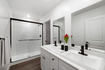 Modern bathroom with dual sinks and a glass shower enclosure.