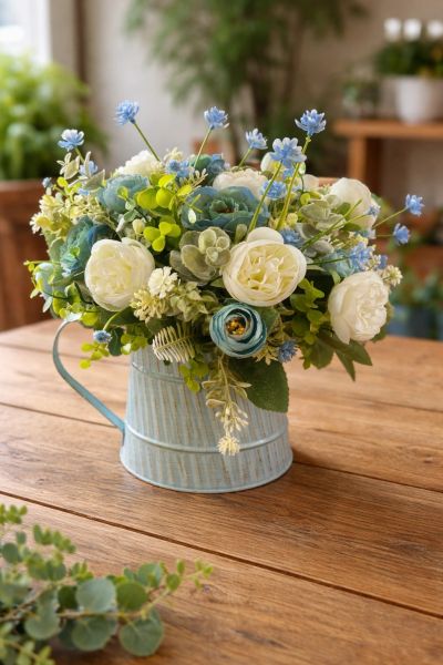 A rustic bouquet with white and blue flowers in a light blue metal vase.