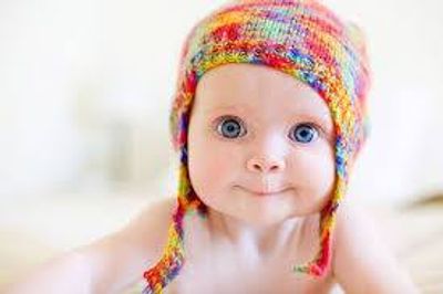 Adorable baby with big blue eyes wearing a colorful knit hat.