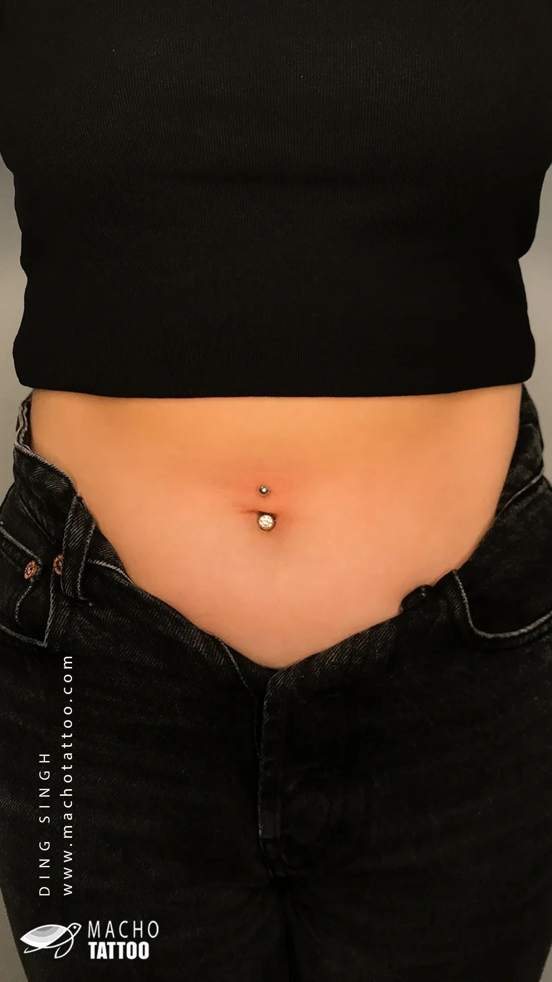 Happy client at Macho Tattoos showing belly button piercing, adorned with a sparkling gemstone stud
