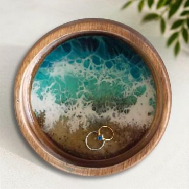 Handcrafted wood ring dish with ocean resin design and rings.