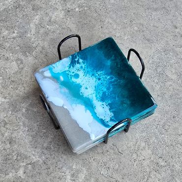 Ocean-inspired ceramic coasters in a black iron stand.