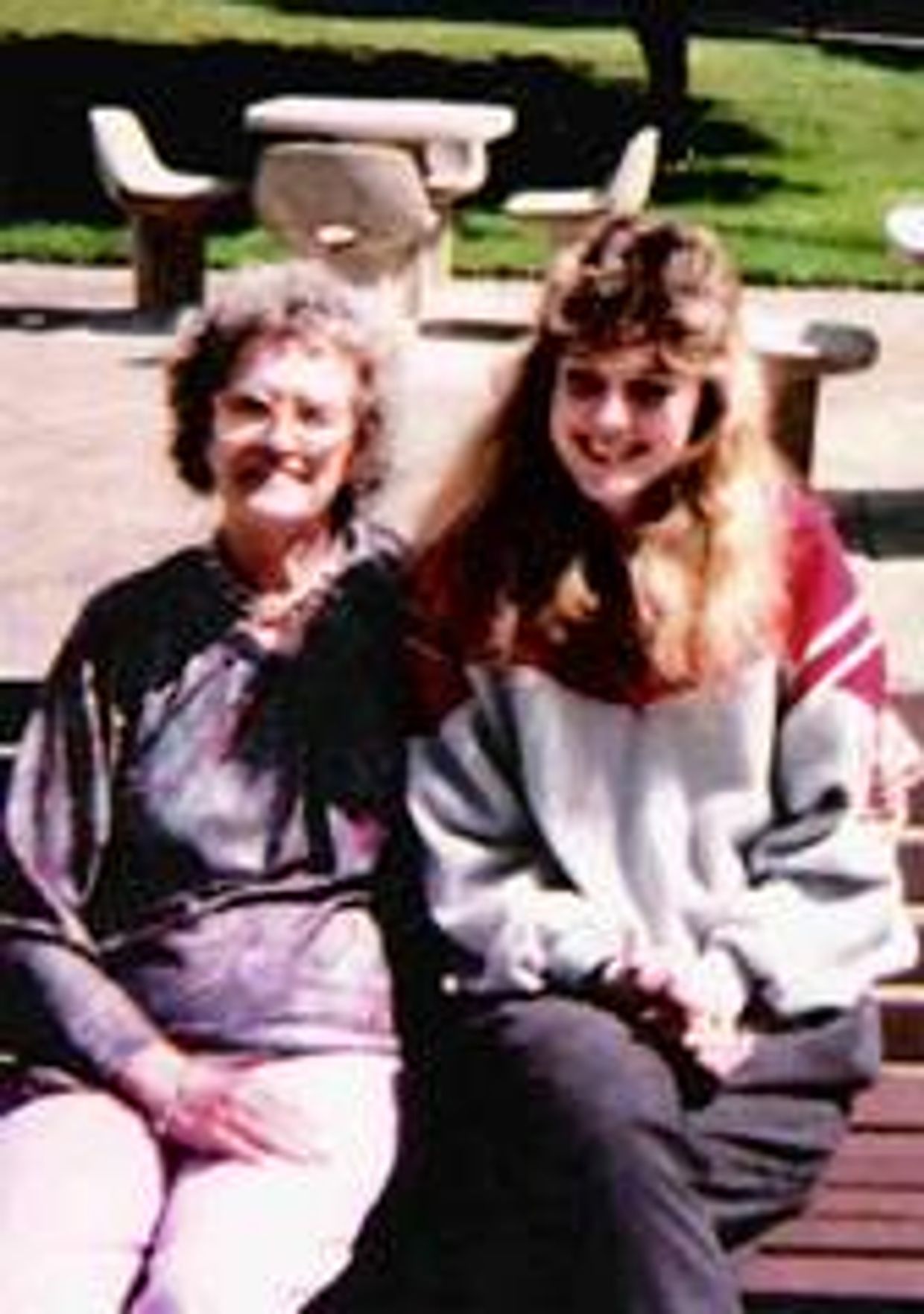 Two women sitting on a park bench.