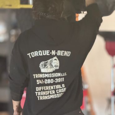 Person wearing a Torque-N-Bend Transmission hoodie working in a garage.