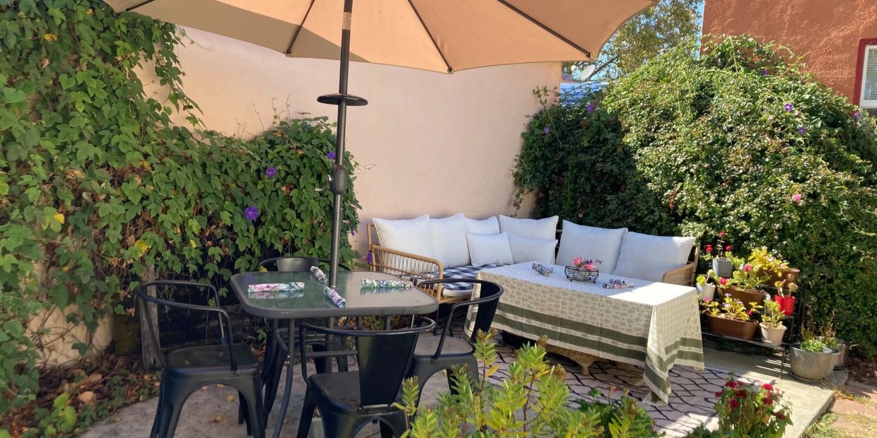 Cozy backyard patio with table, chairs, umbrella, and plants.