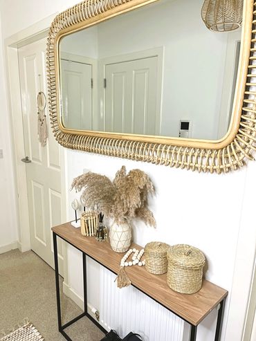 Minimalist entryway with natural decor and a large woven mirror.