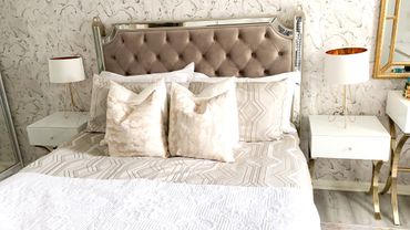 Elegant bedroom with tufted headboard and gold-accented lamps.