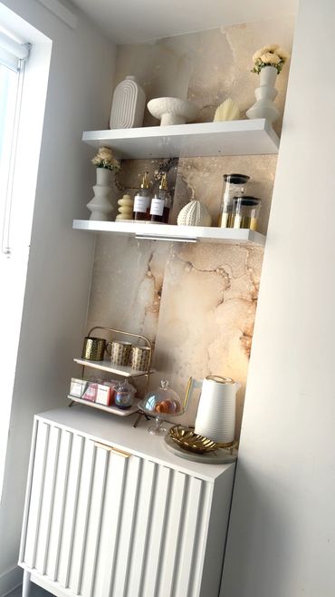 Elegant kitchen corner with white shelves, decorative items, and a coffee setup.