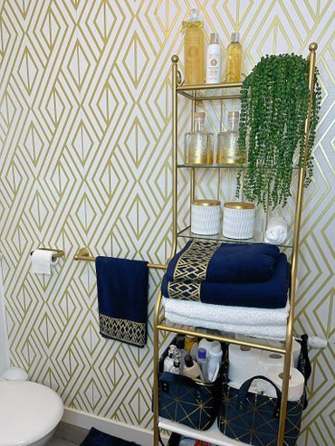 Elegant bathroom corner with gold accents and navy towels.