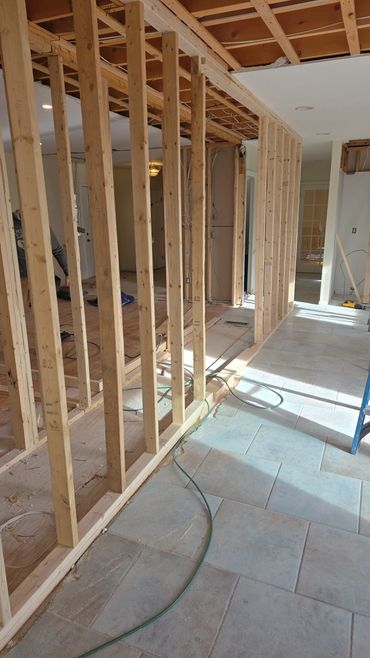 Interior home renovation with exposed wooden framing and tiled floor.
