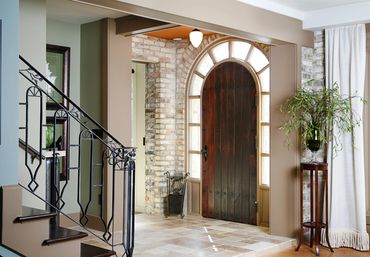 Cozy entrance with wooden arched door and intricate wrought iron staircase railing.