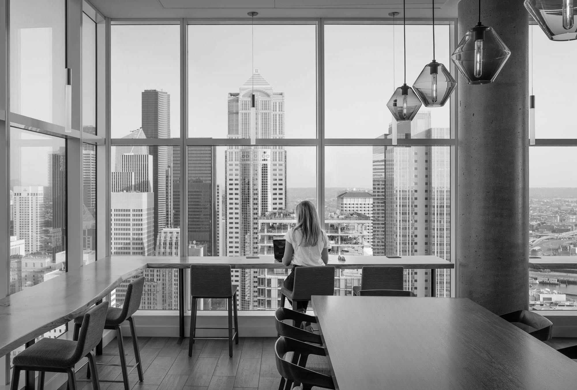 Person working on a laptop in a high-rise office with cityscape view.