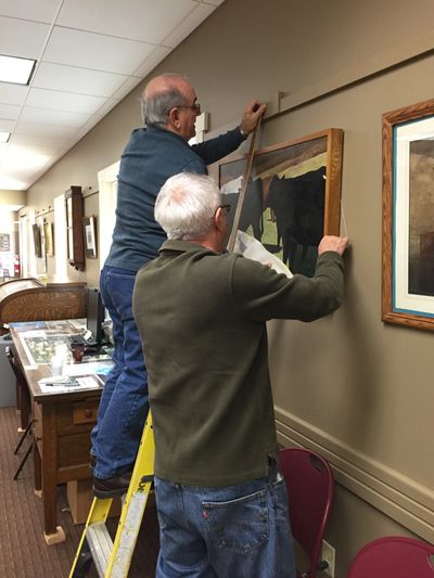 Volunteers hang art in Meeting Room