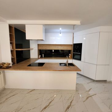 Modern white kitchen with wooden countertops and marble flooring.