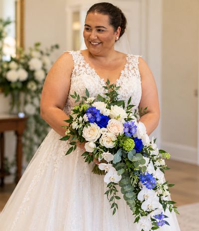 Bride in a white dress holding a vibrant blue and white bouquet.
