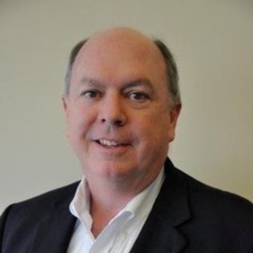 Middle-aged man in business attire smiling.